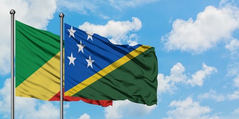 Republic Of The Congo and Solomon Islands flag waving in the wind against white cloudy blue sky...