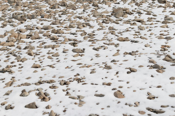 Rocky ground covered with snow, individual stones stick out from under the snow