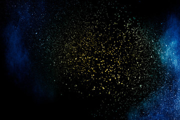 Fototapeta na wymiar Yellow blue powder explosion cloud on black background. Freeze motion of color dust particles splashing.