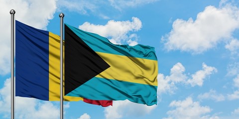 Romania and Bahamas flag waving in the wind against white cloudy blue sky together. Diplomacy...