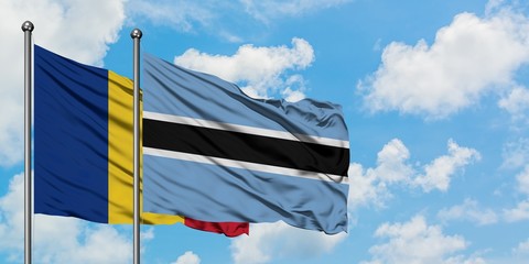 Romania and Botswana flag waving in the wind against white cloudy blue sky together. Diplomacy...