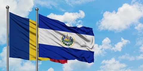 Romania and El Salvador flag waving in the wind against white cloudy blue sky together. Diplomacy...