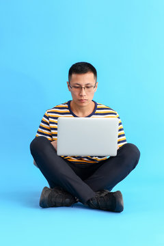 Asian programmer with laptop on color background