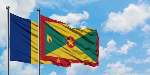 Romania and Grenada flag waving in the wind against white cloudy blue sky together. Diplomacy concept, international relations.