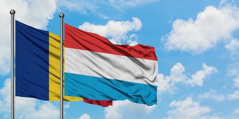 Romania and Luxembourg flag waving in the wind against white cloudy blue sky together. Diplomacy...