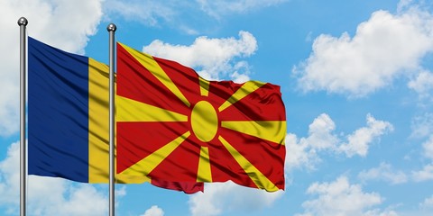 Romania and Macedonia flag waving in the wind against white cloudy blue sky together. Diplomacy...