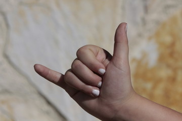 Mano de niña con las uñas pintadas de blanco realizando distintos signos.
