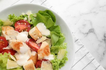 Tasty Caesar salad on white marble table, top view