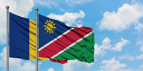 Romania and Namibia flag waving in the wind against white cloudy blue sky together. Diplomacy concept, international relations.