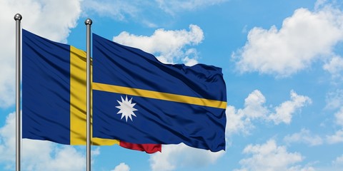Romania and Nauru flag waving in the wind against white cloudy blue sky together. Diplomacy...