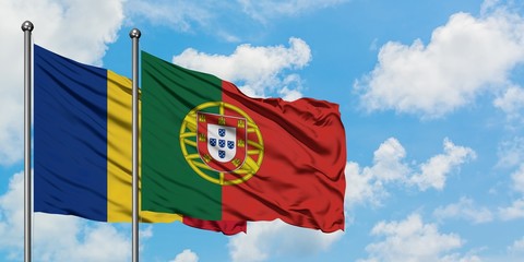 Romania and Portugal flag waving in the wind against white cloudy blue sky together. Diplomacy...
