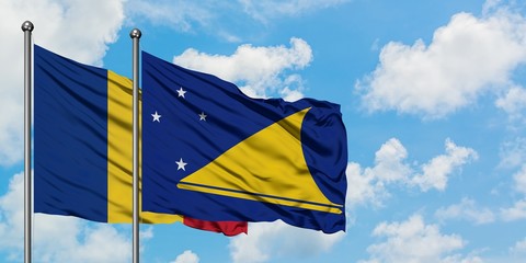 Romania and Tokelau flag waving in the wind against white cloudy blue sky together. Diplomacy...