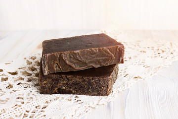 Handmade lye soap bars, healing feminine concept. Spa natural body care accessories. Eco organic lye soap with olive oil on the rustic wooden background. Coal tar soap for skin care routine.