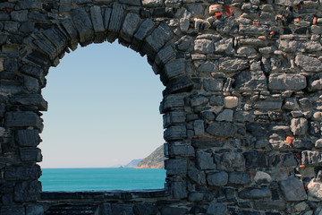 Arco e muro in pietra con vista mare - obrazy, fototapety, plakaty