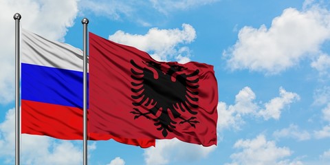 Russia and Albania flag waving in the wind against white cloudy blue sky together. Diplomacy...