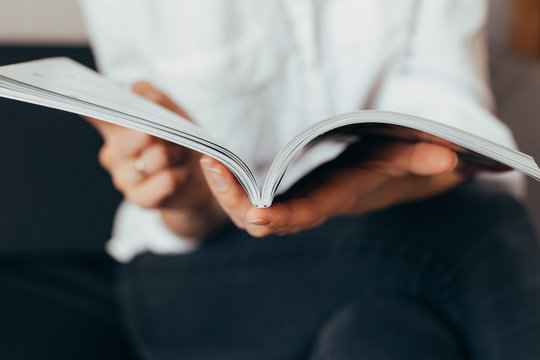 Beautiful female hands hold an open book or magazine in the room - Powered by Adobe