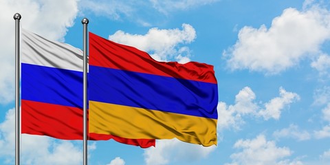 Russia and Armenia flag waving in the wind against white cloudy blue sky together. Diplomacy concept, international relations.