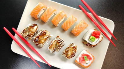 Beautiful of Philadelphia and Canada sushi rolls with red chopsticks on a plate.