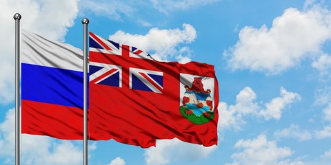 Russia and Bermuda flag waving in the wind against white cloudy blue sky together. Diplomacy...