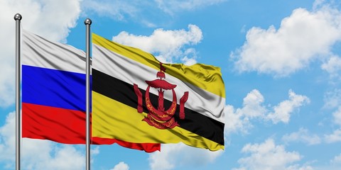 Russia and Brunei flag waving in the wind against white cloudy blue sky together. Diplomacy...