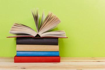 Simple composition of many hardback books, raw of books on wooden table and light green background