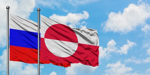 Russia and Greenland flag waving in the wind against white cloudy blue sky together. Diplomacy concept, international relations.