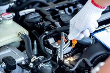 Close up of a car mechanic checking oil level in a mechanical workshop