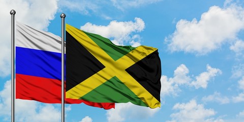 Russia and Jamaica flag waving in the wind against white cloudy blue sky together. Diplomacy concept, international relations.
