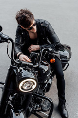 high angle view of young man in leather jacket sitting on motorcycle