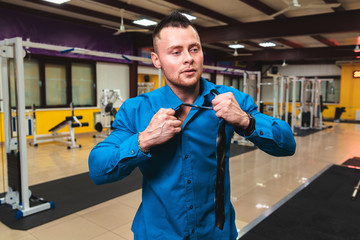 Handsome young man in blue shirt and tie in gym