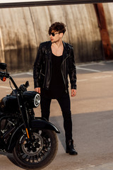 full length view of motorcyclist standing near black motorcycle and looking away