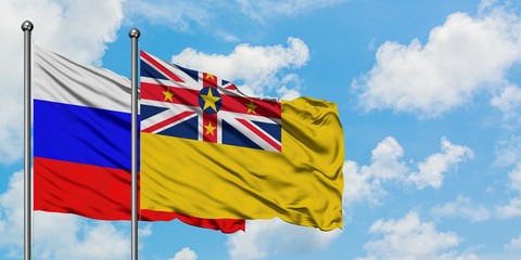 Russia and Niue flag waving in the wind against white cloudy blue sky together. Diplomacy concept, international relations.