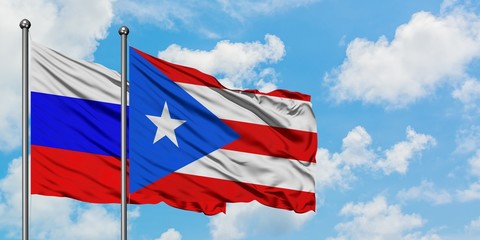Russia and Puerto Rico flag waving in the wind against white cloudy blue sky together. Diplomacy concept, international relations.