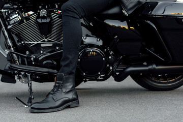 Fototapeta na wymiar cropped view of man in black boot sitting on motorcycle