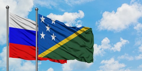 Russia and Solomon Islands flag waving in the wind against white cloudy blue sky together. Diplomacy concept, international relations.
