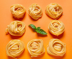 Dry pasta with basil on color background