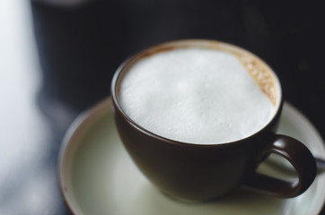 close up modern hot black coffee the cappuccino on dark background with coffee bubble foam pattern and texture in black cup looking and feel so delicious on glasses table in coffee shop.