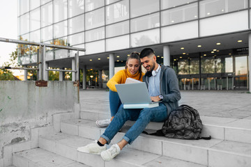 portrait of university students using laptop computer outdoors