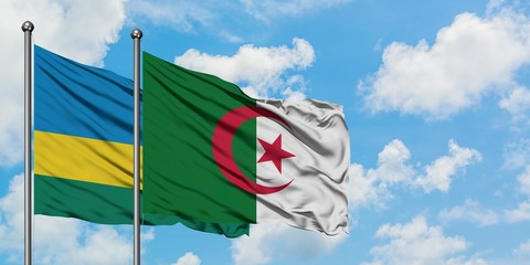 Rwanda and Algeria flag waving in the wind against white cloudy blue sky together. Diplomacy...