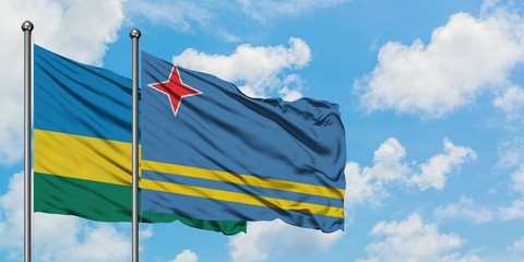 Rwanda and Aruba flag waving in the wind against white cloudy blue sky together. Diplomacy concept, international relations.