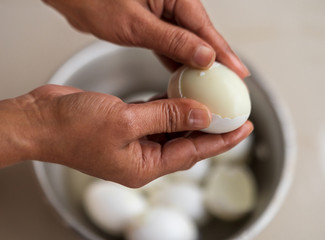 Peel Boiled Egg. Closeup of hand of Indian woman peeling a hard boiled egg in the kitchen. Egg...