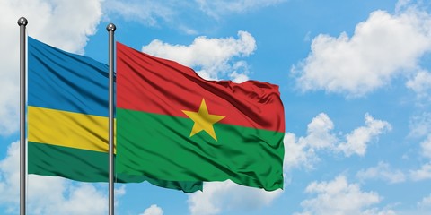 Rwanda and Burkina Faso flag waving in the wind against white cloudy blue sky together. Diplomacy...
