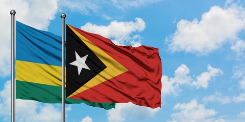 Rwanda and East Timor flag waving in the wind against white cloudy blue sky together. Diplomacy concept, international relations.