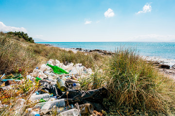 plastic and garbage glass bottles at a beach in the mediterranean sea of Greece