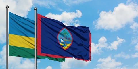 Rwanda and Guam flag waving in the wind against white cloudy blue sky together. Diplomacy concept, international relations.