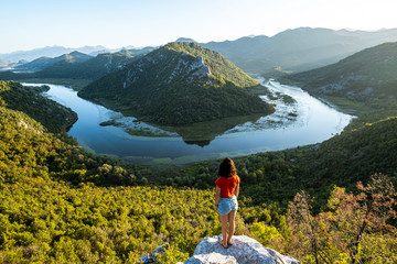 Lady looking over Lake Skadar in Montenegro during a beautiful sunset  - obrazy, fototapety, plakaty