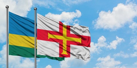 Rwanda and Guernsey flag waving in the wind against white cloudy blue sky together. Diplomacy concept, international relations.