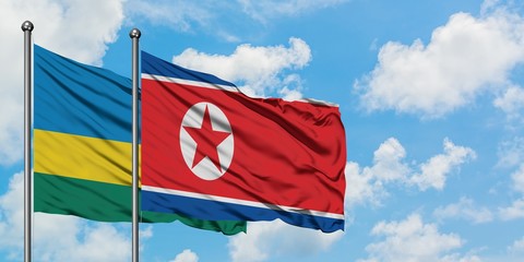 Rwanda and North Korea flag waving in the wind against white cloudy blue sky together. Diplomacy concept, international relations.