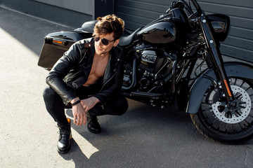Fototapeta na wymiar muscular young man sitting near motorcycle and looking away