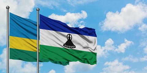 Rwanda and Lesotho flag waving in the wind against white cloudy blue sky together. Diplomacy...
